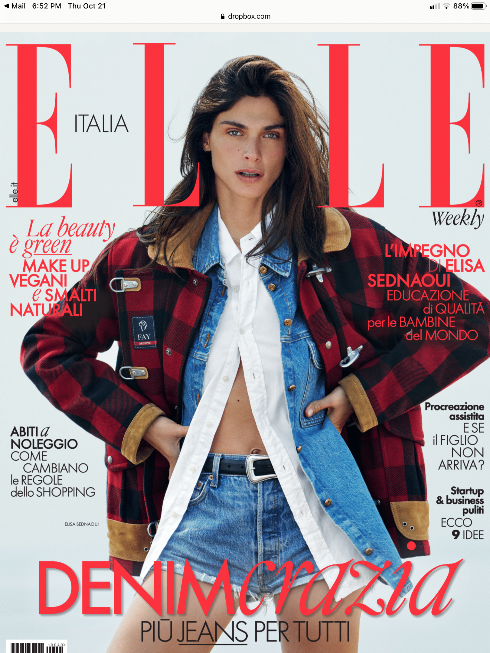 A person modeling a red and black plaid jacket over a white shirt and blue denim jeans, photographed on the cover of ELLE Italia Weekly magazine. The cover has large red ELLE branding and Italian text.