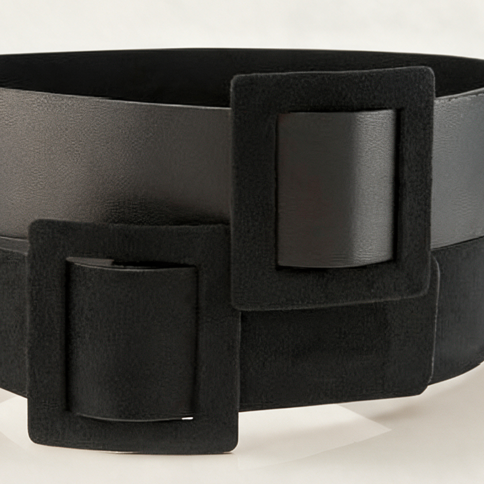 A wide black belt with a double-buckle design, featuring matte and satin finishes, photographed on a clean white background.